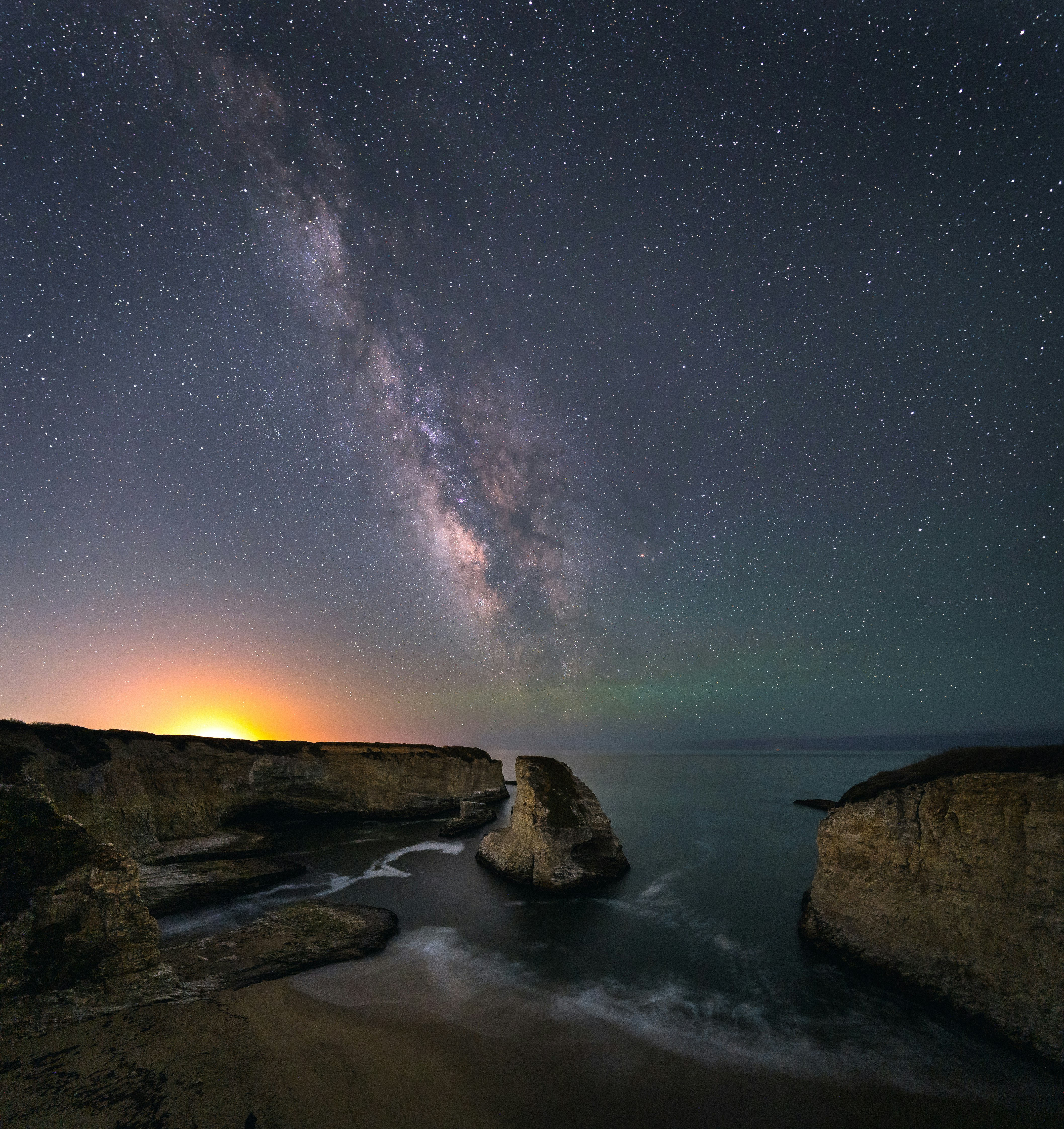 brown rock formation on body of water under starry night